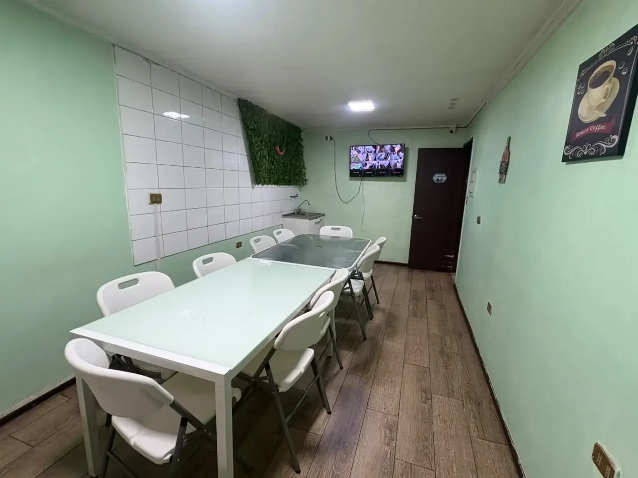 Comedor de Eduardo Aranis con mesas y sillas blancas entre paredes verdes.