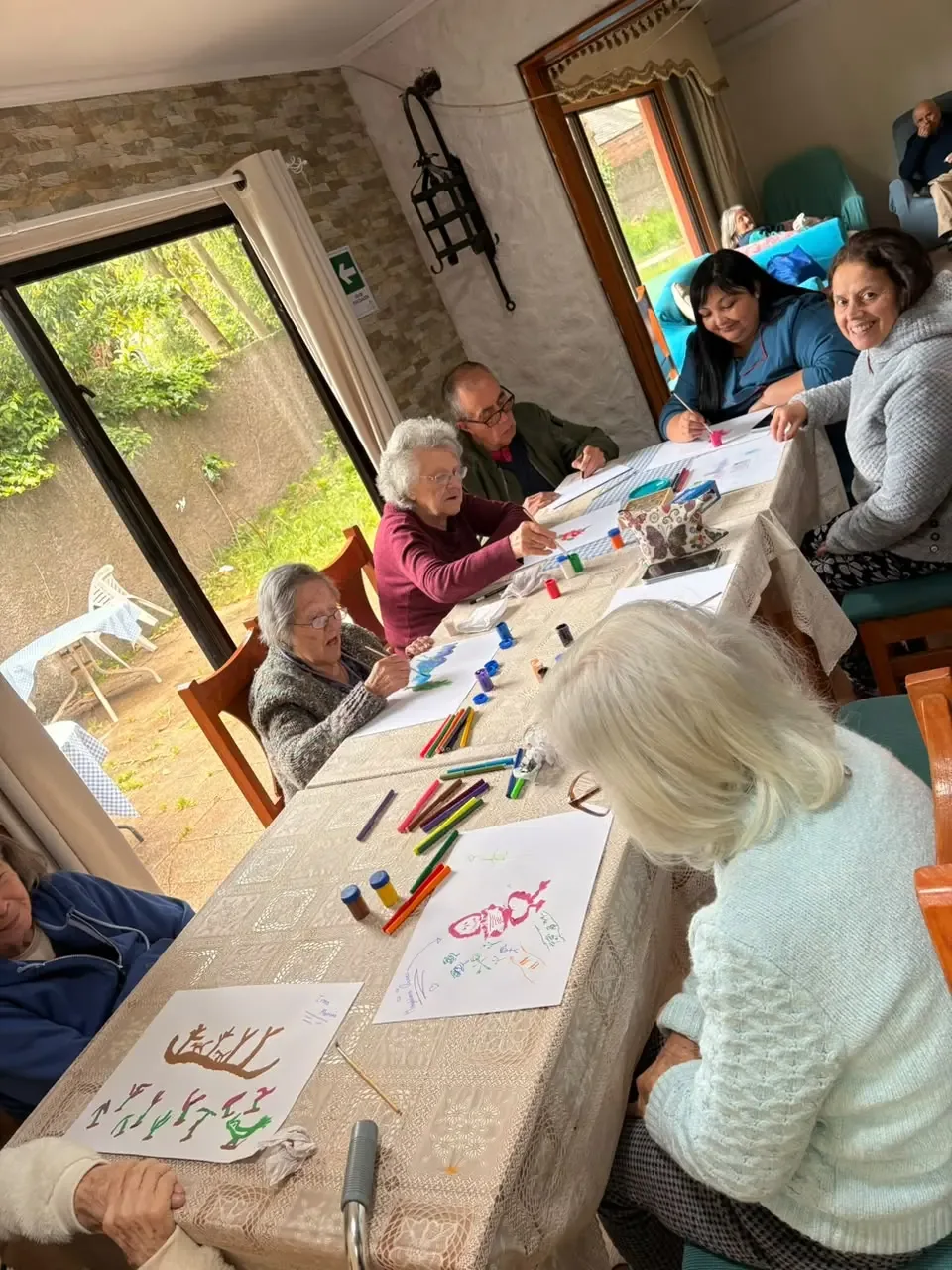 Personas mayores y acompañantes comparten una actividad de pintura en el comedor de Puertas de Alcalá.