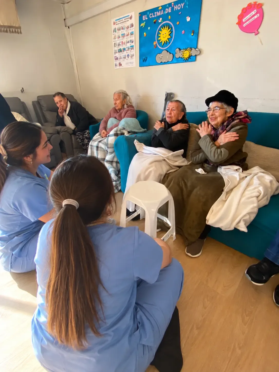 Cuidadoras con uniforme azul acompañan a personas mayores durante una actividad compartida en la residencia.